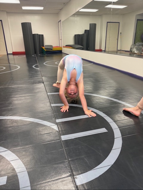 A young Inspirations Academy student practicing a bridge during acro class.