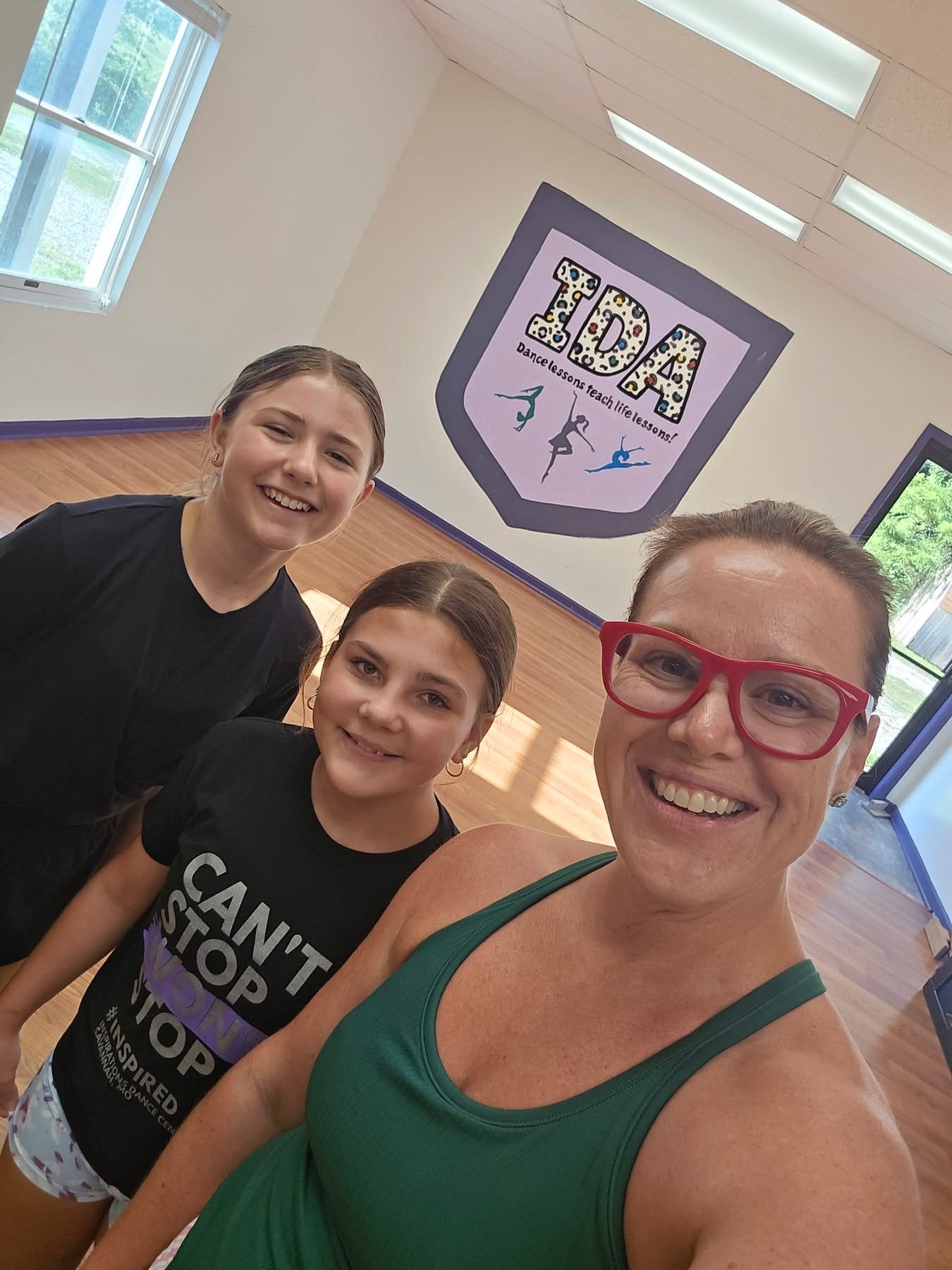 A staff member and students in one of the Inspirations Academy studio rooms, with the Dance Lessons Teach Life Lessons wall mural.