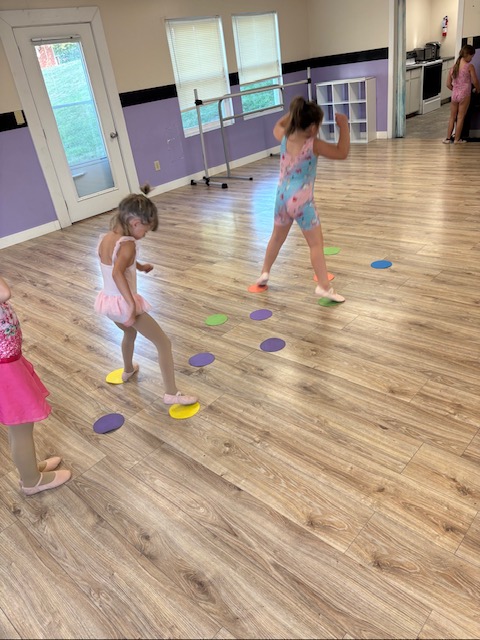 Preschool age Inspirations Academy dancers stepping across colorful floor spots during class.