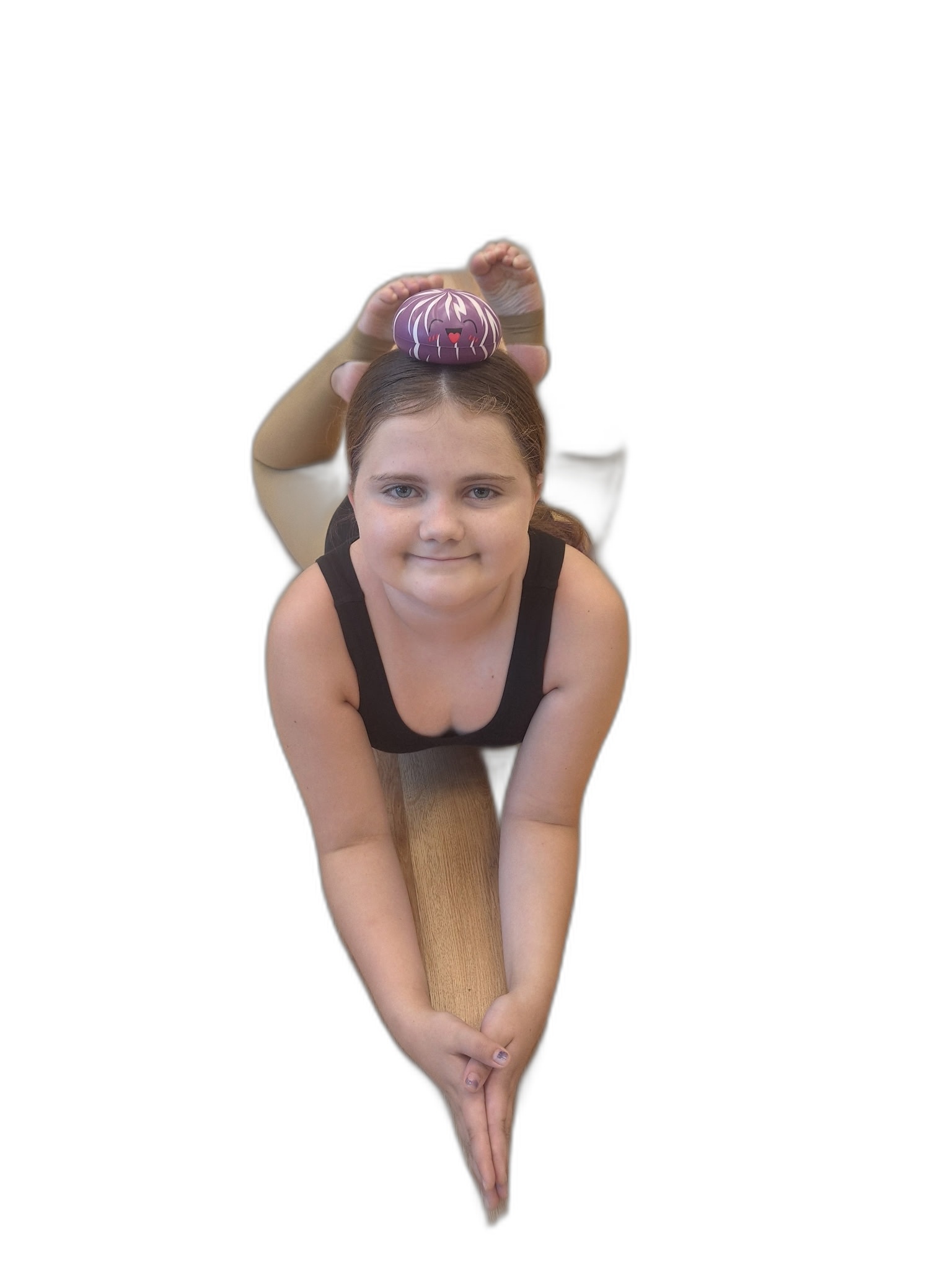 A student balancing the Dancing With Dumplings plush toy near her head during a stretch.