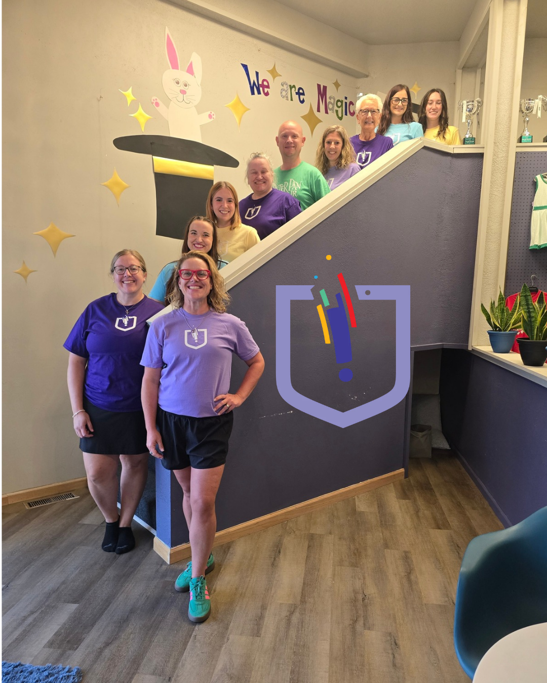 The Inspirations Academy staff team standing together by the studio's We Are Magic mural