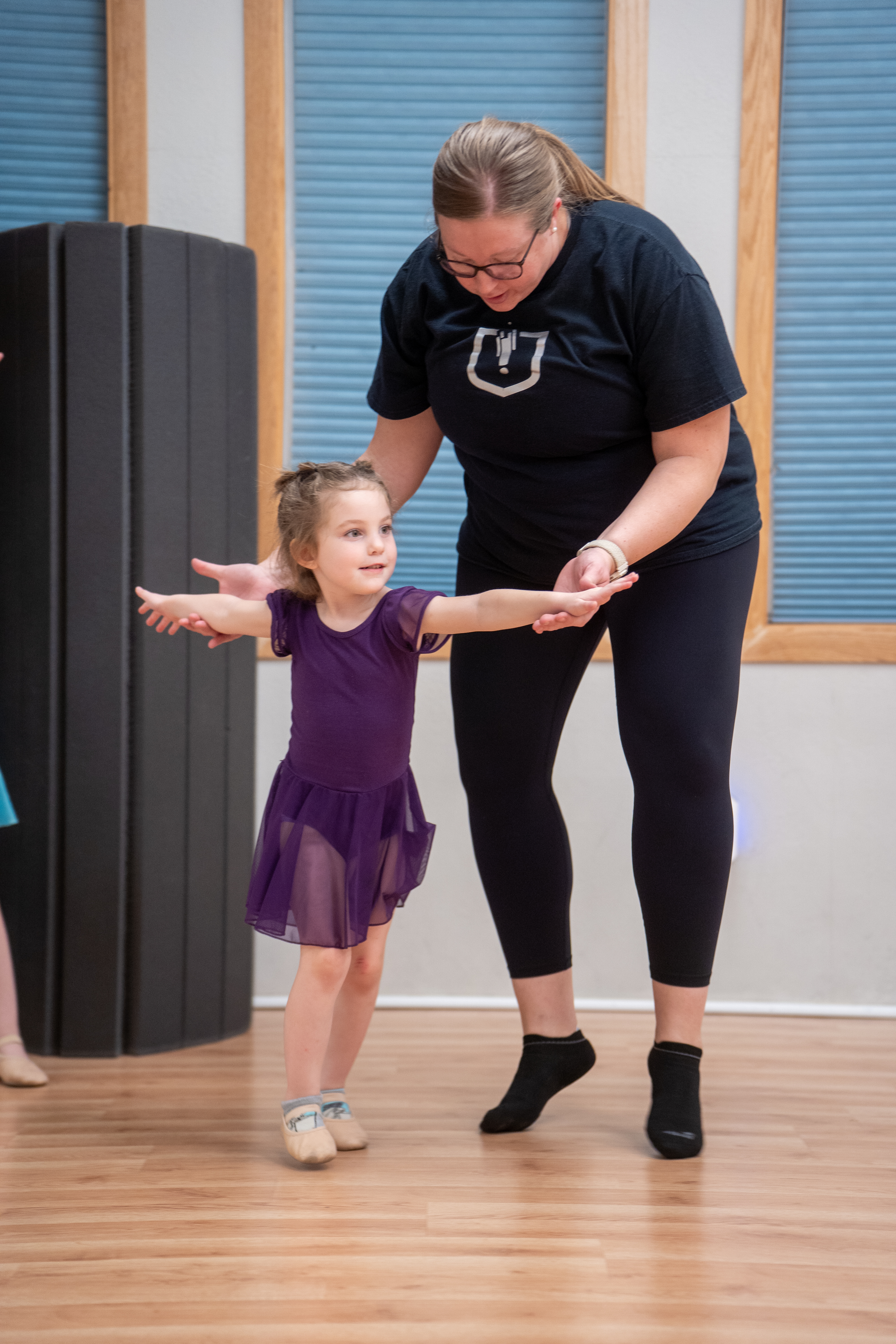 An Inspirations Academy instructor helping a young dancer with her arm positioning